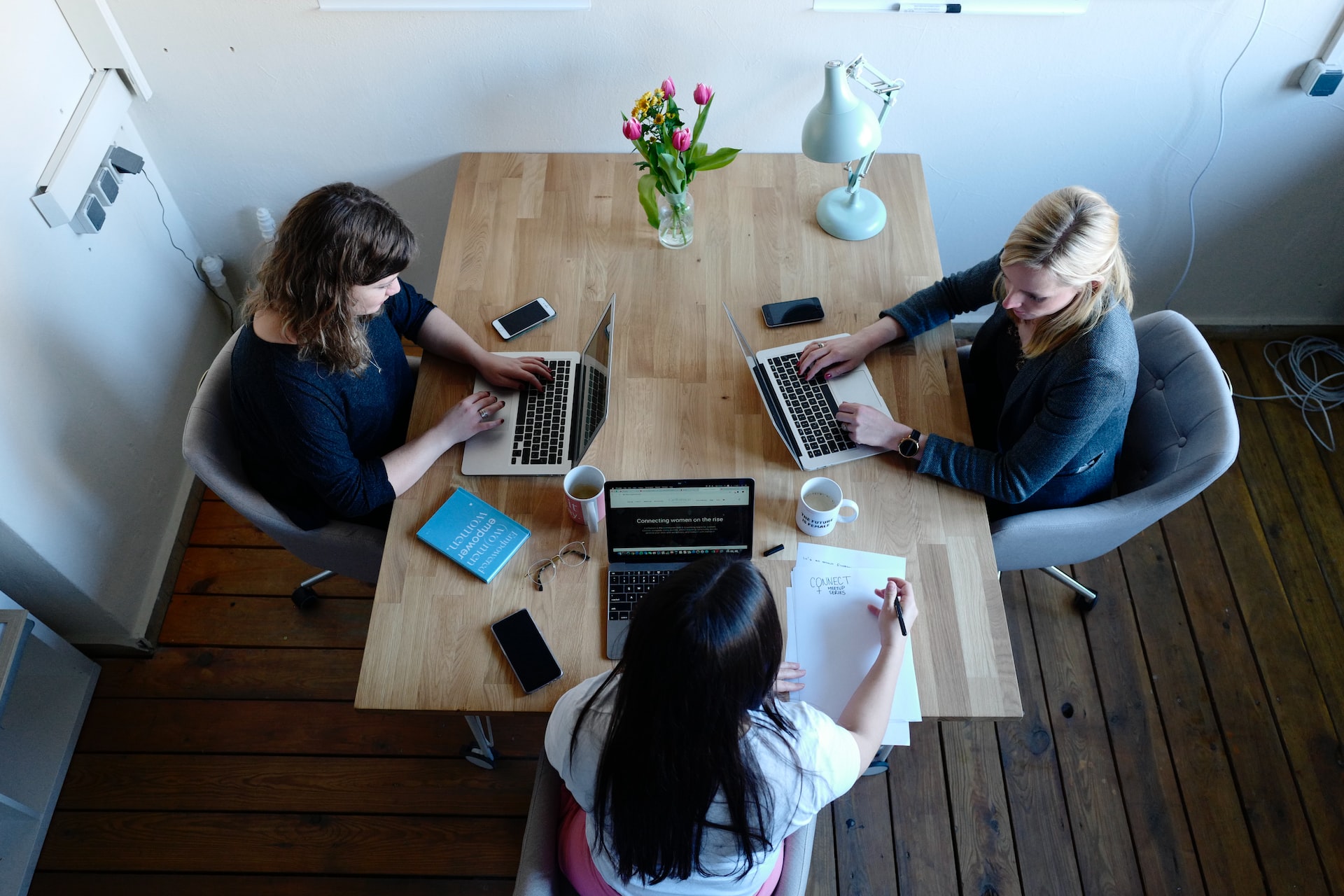 3 mujeres trabajando en una mesa de madera