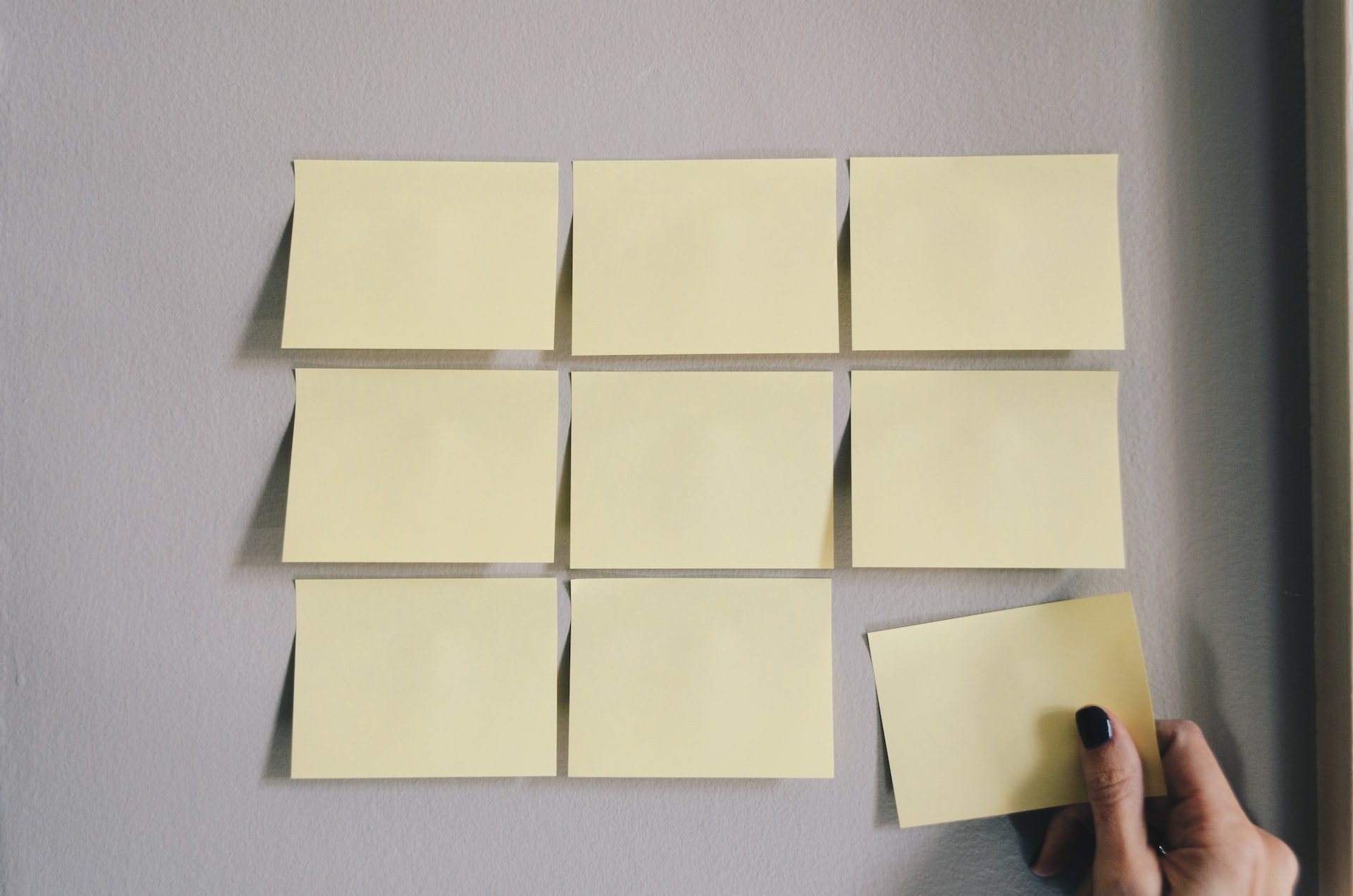 mano colocando 9 post-it, formando cuadrado
