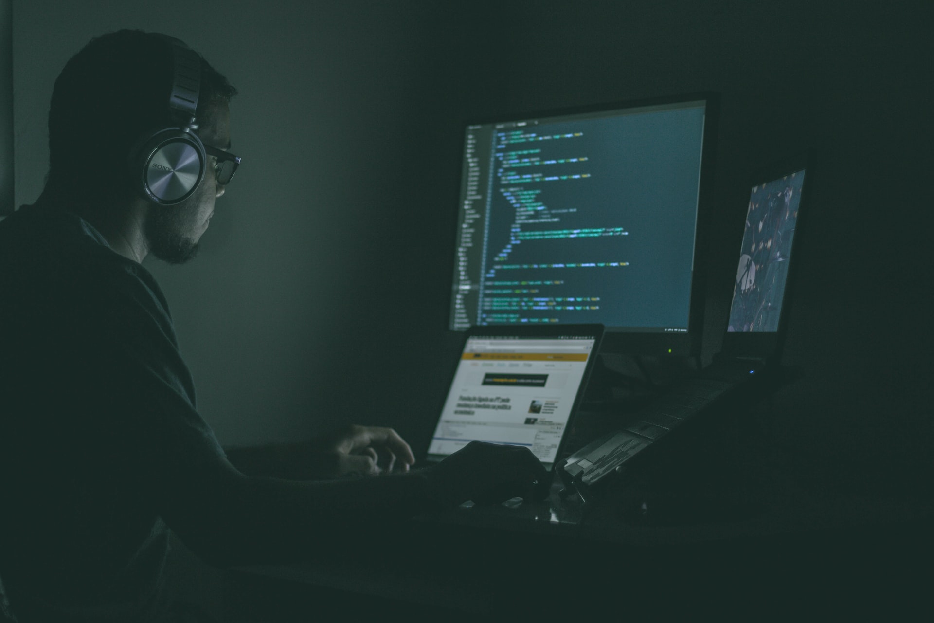 programador con tres pantallas y poca luz