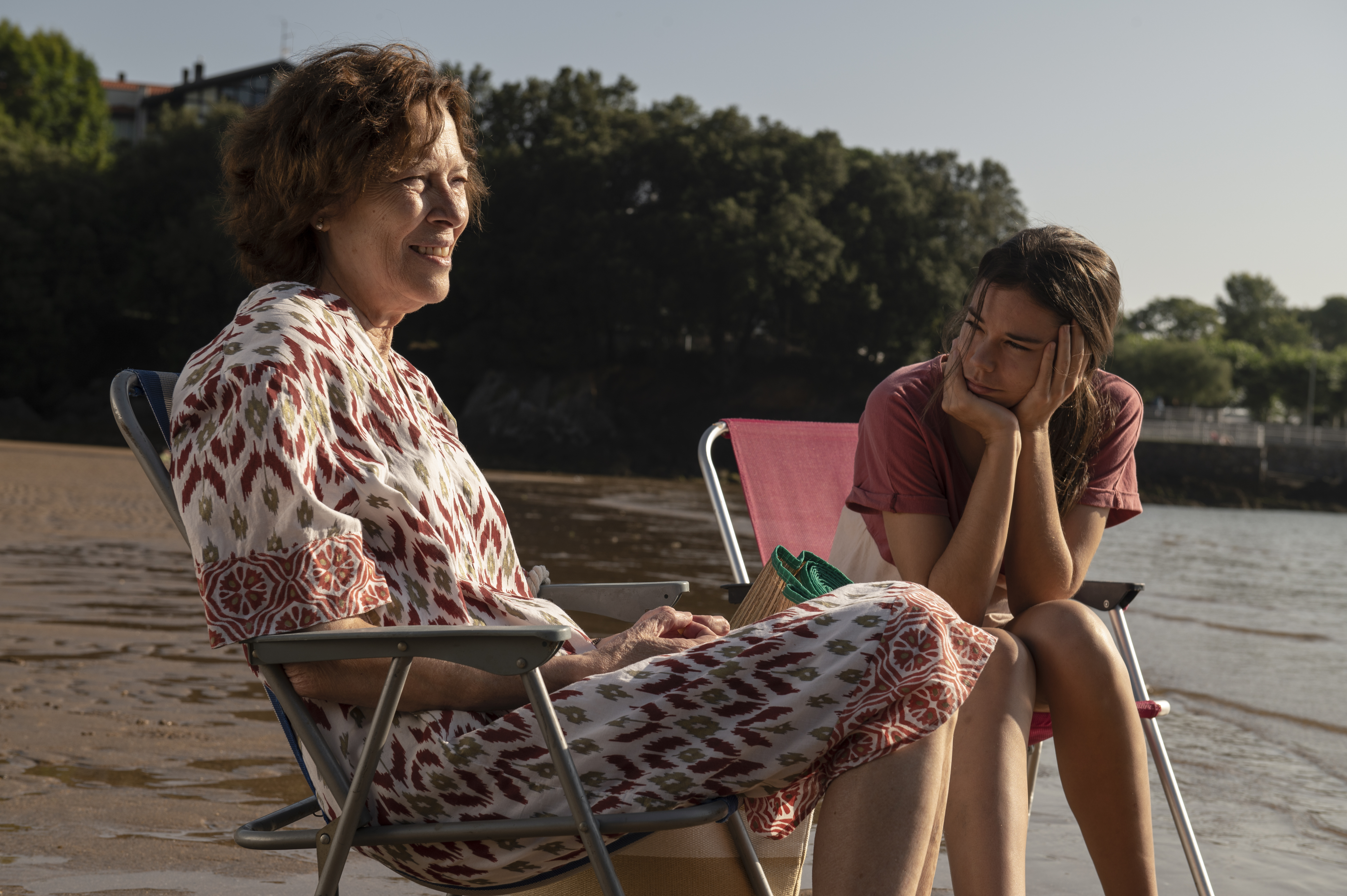 Fotograma de la película Cinco Lobitos. Dos mujeres sentadas en sillas de playa en la orilla