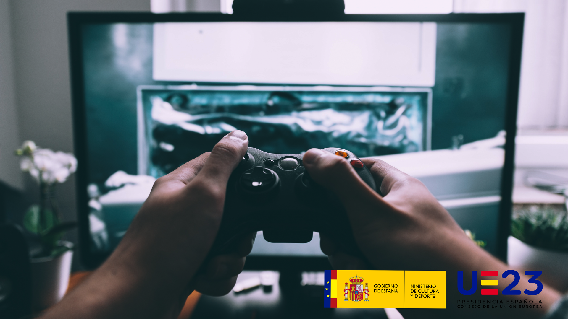 Banner de la jornada Cultura y Videojuegos. Primer plano de unas manos sujetando un mando de videoconsola