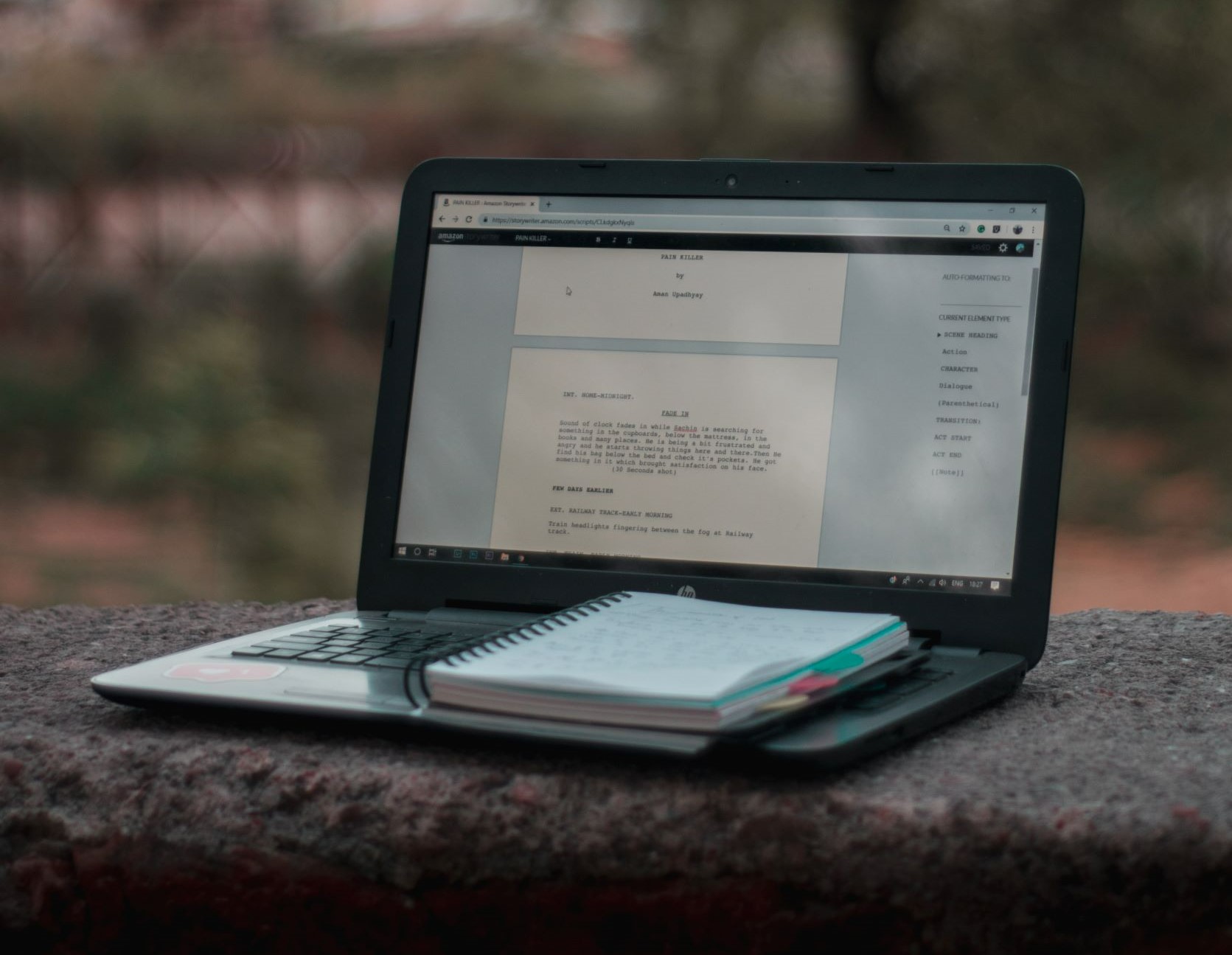 ordenador portátil con un guion en la pantalla y un cuaderno apoyado sobre el teclado