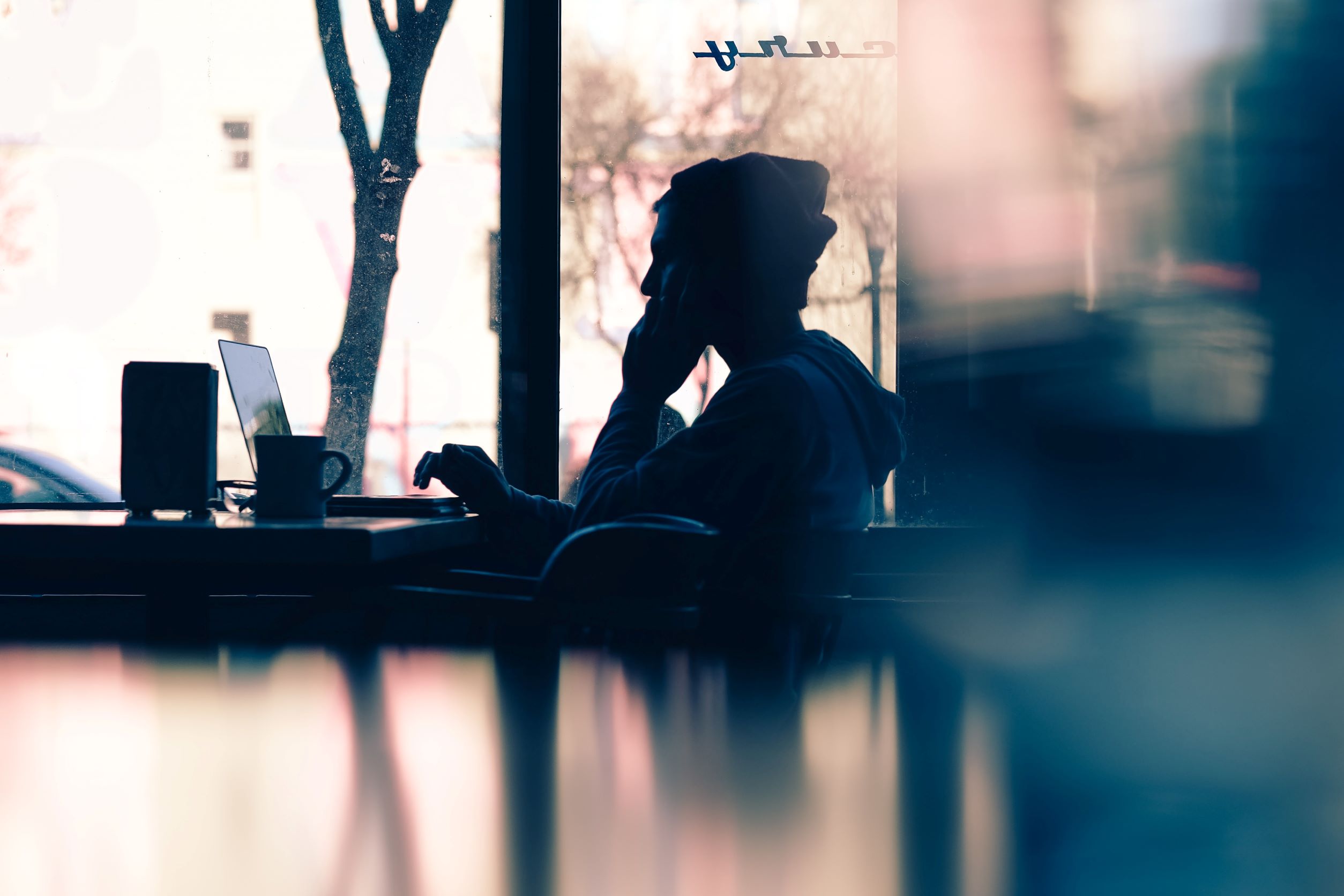 Persona escribiendo en un ordenador en una cafetería