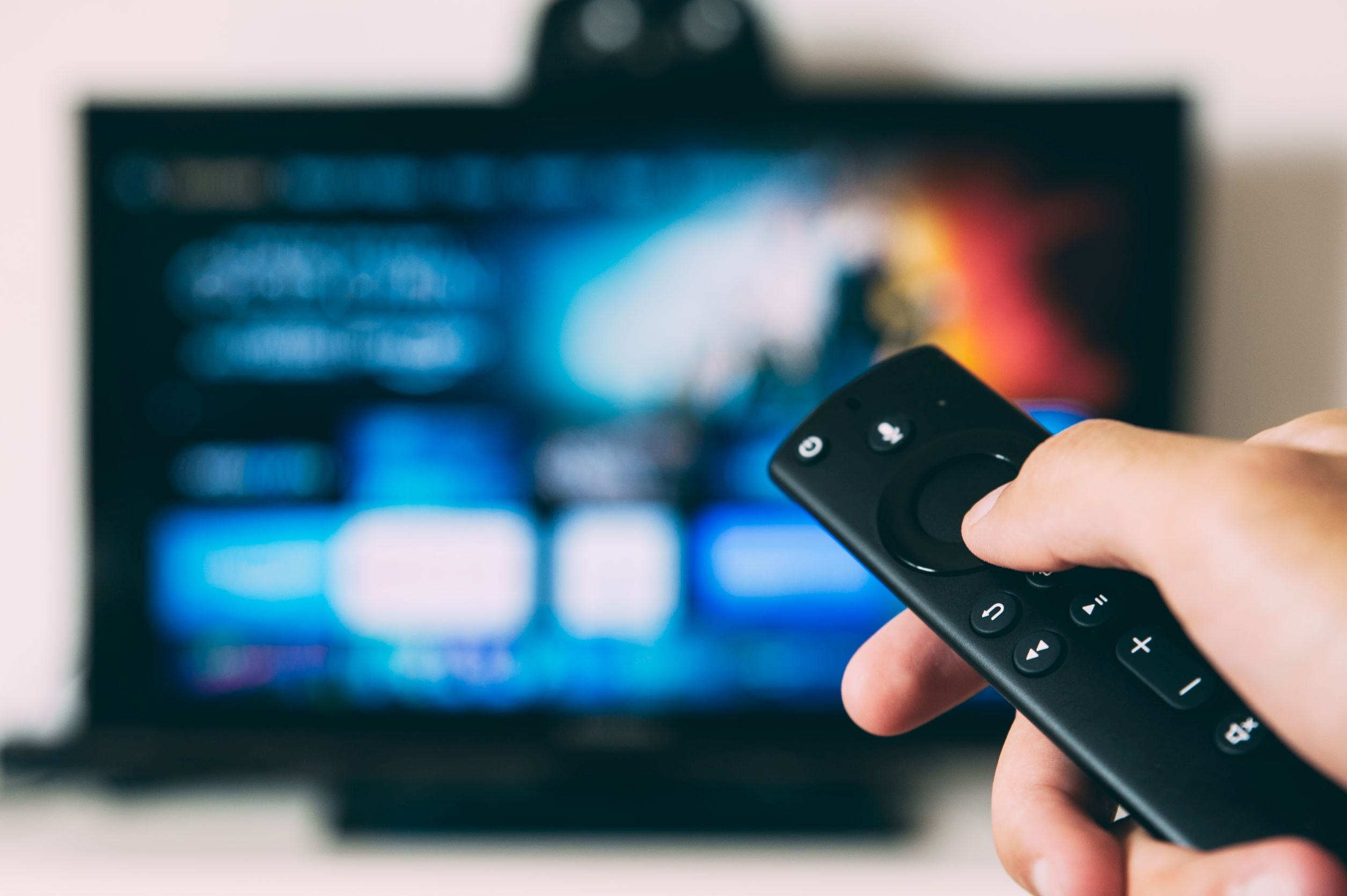 imagen de un mando a distancia en primer plano y una televisión en segundo plano