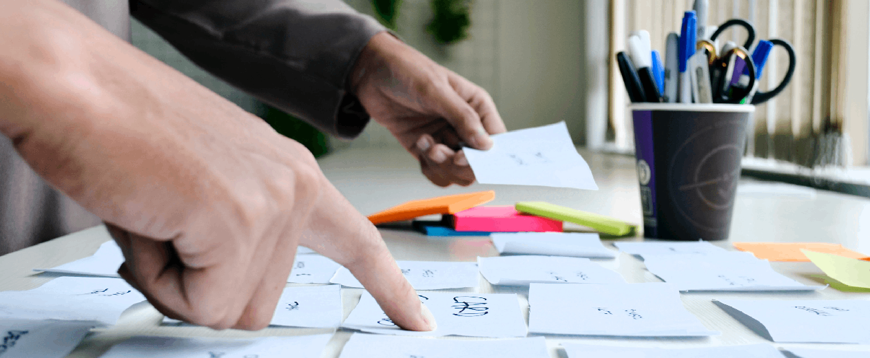 Primer plano de las manos de unas personas trabajando sobre tarjetas con ideas