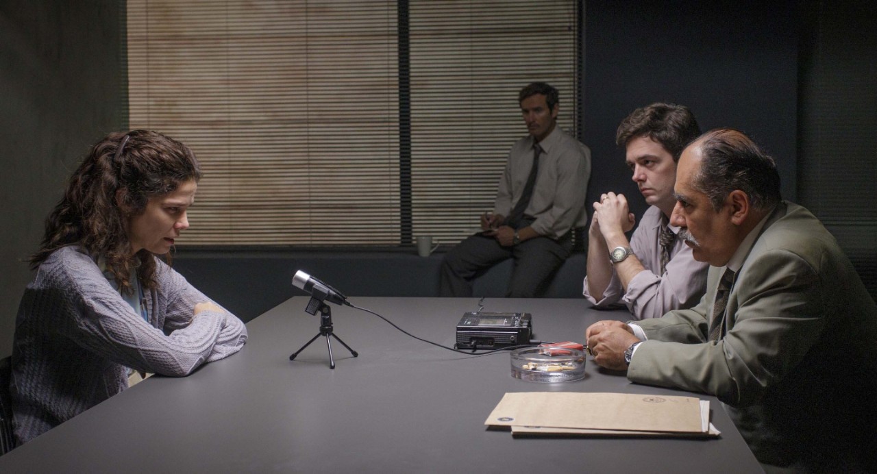Fotograma de la película Llegaron de noche. Cuatro personas en una sala de interrogatorios.