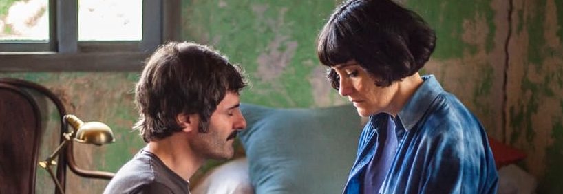 Fotograma de la película Malencolía. Una mujer sentada en una cama y un hombre de rodillas delante de ella