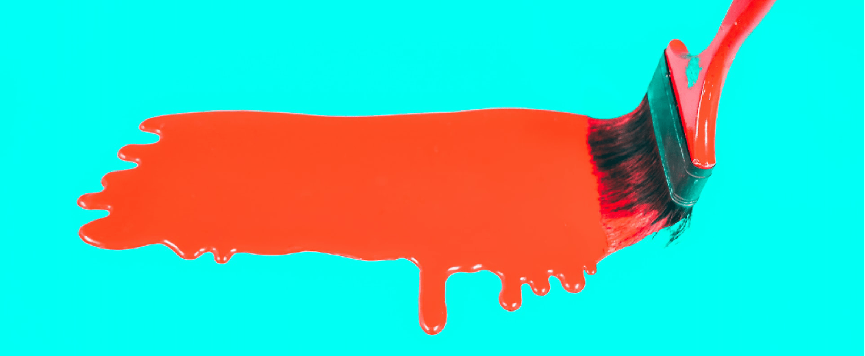 Imagen de una brocha pintando con color anaranjado sobre un fondo de color turquesa