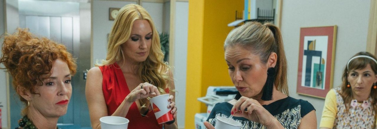 Fotograma de la película Camera Café. Cuatro mujeres delante de una máquina de café en una oficina
